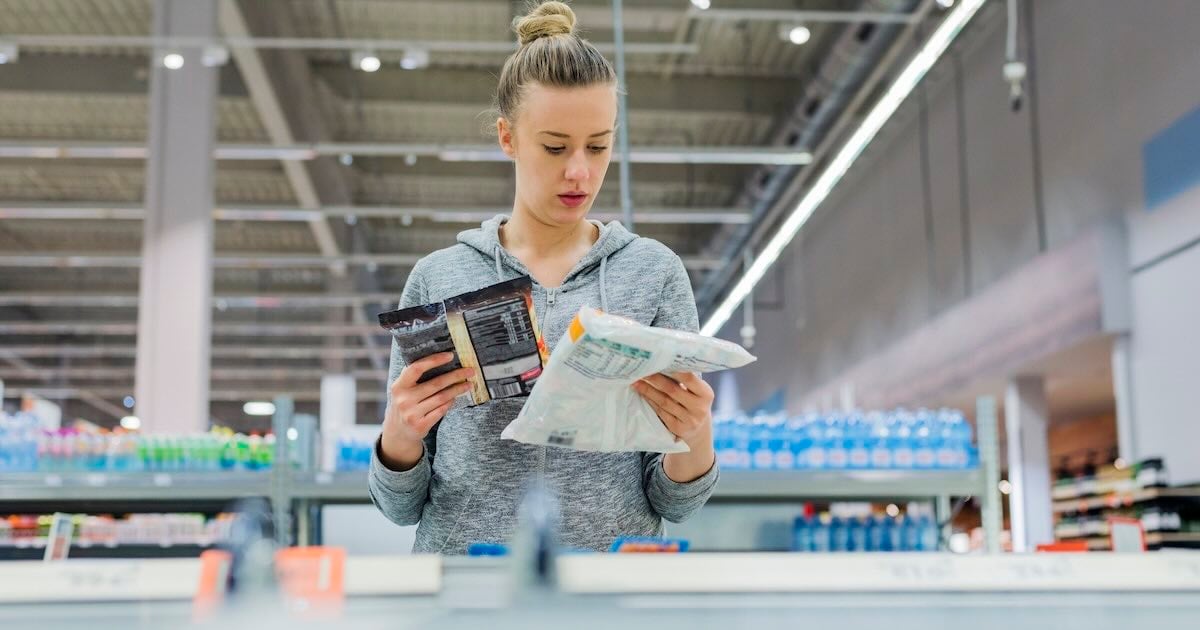 woman comparing frozen food options in a grocery store
