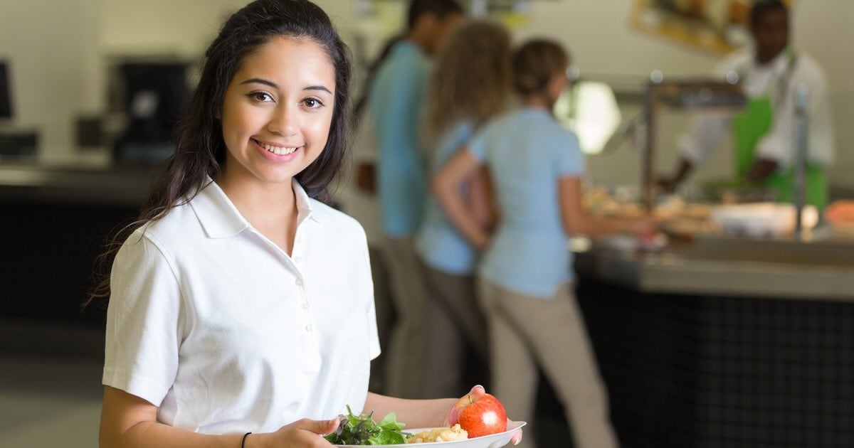 student holding cafeteria plate with food