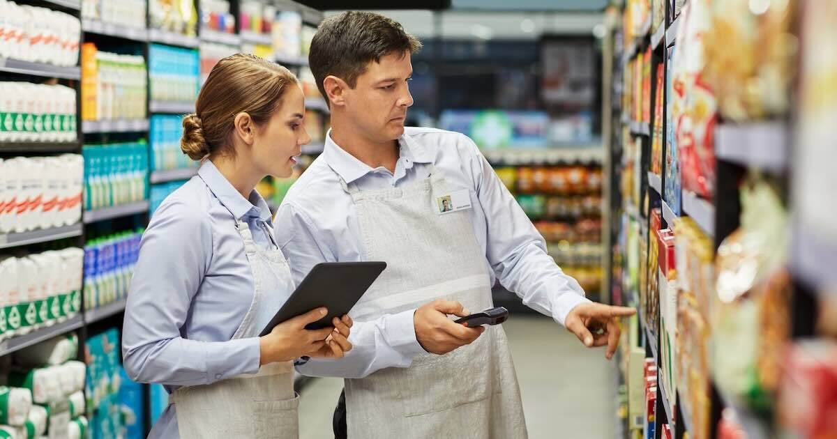 two grocery workers looking at a shelf