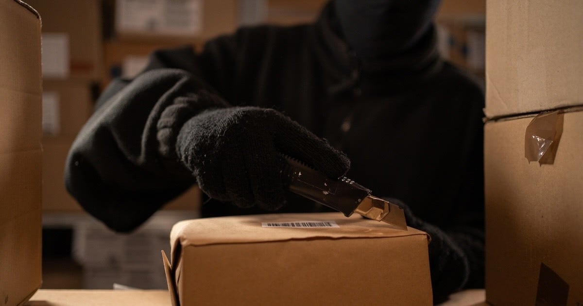 cargo thief opening a box with a box cutter