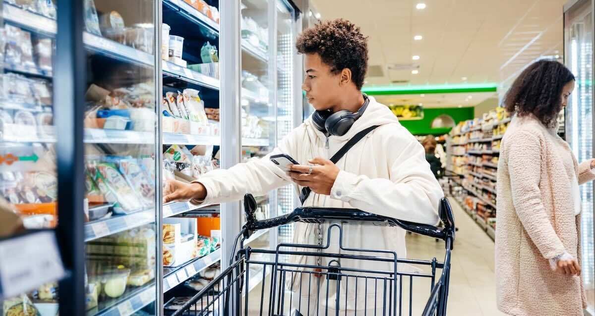 another person reaching into grocery store freezer